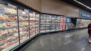 Açougue de supermercado com balcões de carnes refrigeradas, placas de ofertas e letreiro Casa de Carnes.