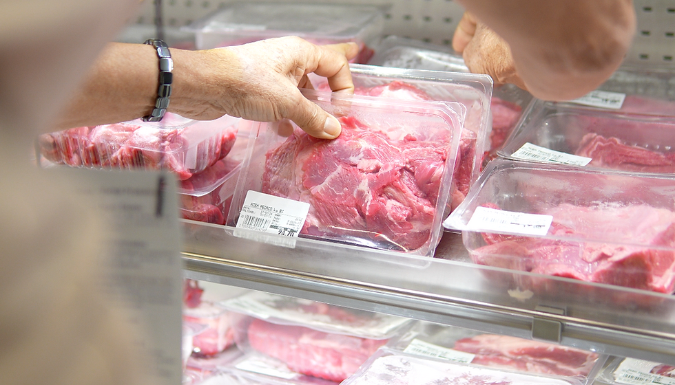 Mãos escolhem carne crua embalada em bandejas no açougue do supermercado, com etiquetas e geladeira fria.
