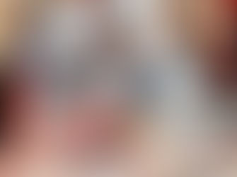 Chef de jaleco branco corta uma grande peça de carne numa mesa, enquanto público observa atento em feira com fundo vermelho.
