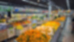 Feira de supermercado com frutas e legumes coloridos; placas de oferta APROVEITE e preços em reais, ambiente iluminado.