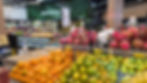 Hortifruti de mercado com pilhas de laranjas, limões e pitayas, placas de preços e iluminação moderna.