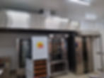 Coifa e Forno em padaria e estante de pães em uma padaria. Design moderno em inox, ambiente iluminado. Texto visível: equipamento exclusivo Hiperpan.