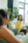 A therapist in a vibrant yellow blazer smiling at her client while seated