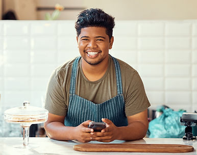 Smiling barista using smartphone at cafe counter