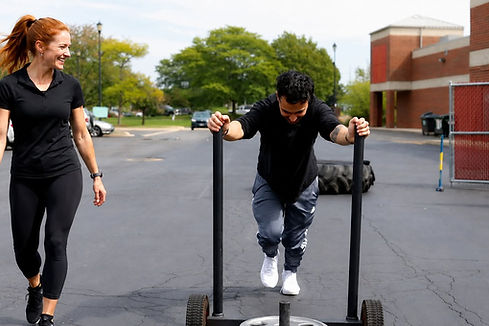 Female personal trainer coaching a client through a muscle-building strength training workout at Starck Fitness in Naperville, Illinois.