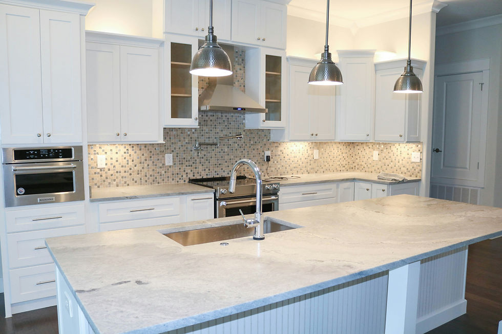Modern kitchen with white cabinets, mosaic tile backsplash, stainless steel oven, and large island under pendant lights, creating a sleek ambiance.