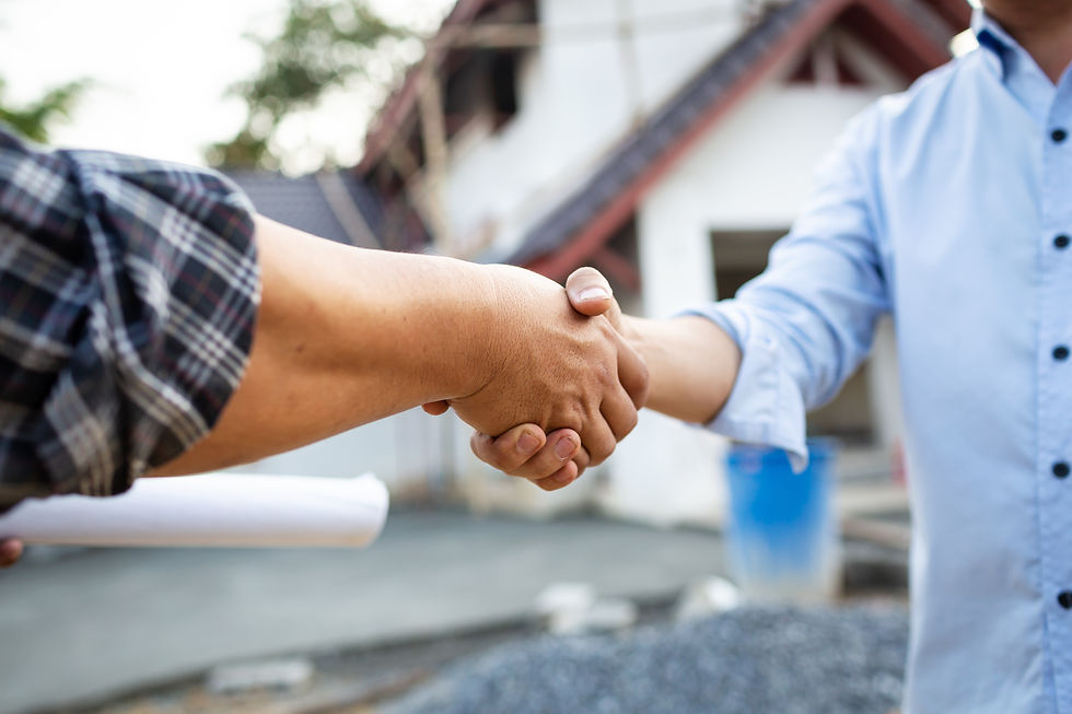 Two people shaking hands outside, one in plaid, another in blue, with a house and blue barrels in the background; cooperative mood.