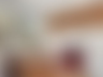 Modern kitchen with marble backsplash, red oven, wood cabinets, and island. Large window shows a sunlit garden. Warm, inviting atmosphere.