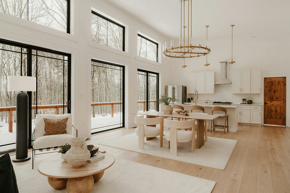 Bright modern kitchen and dining area with large windows overlooking snowy trees, white cabinets, wood accents, and a cozy neutral mood