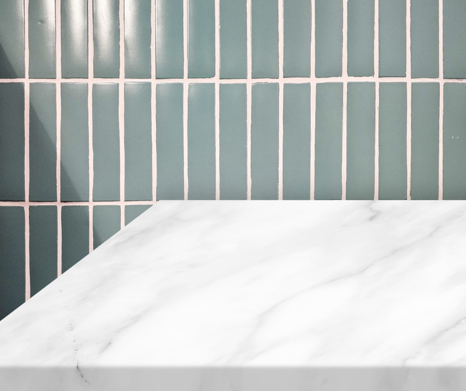 Marble surface in front of a teal tiled wall with white grout. The setting is simple and clean with a modern, minimalistic feel.