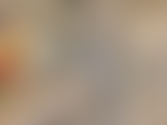 Bathroom with gray cabinets, marble countertop, and a vase of pink tulips. Glass jars on counter, white tiled shower in the background.