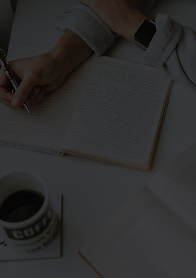 person writing on notebook beside mug_ed