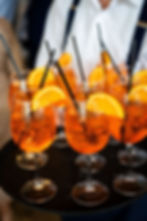 Five wine glasses with orange cocktails and ice on a white table, creating a refreshing and festive ambiance. spritz welcome cocktails