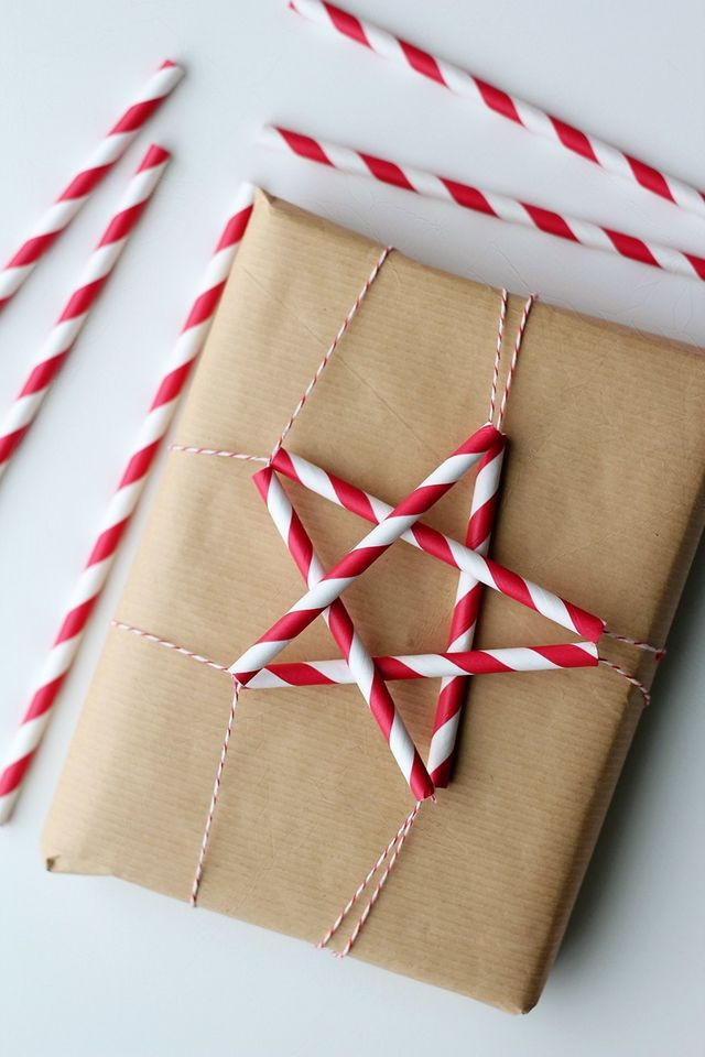 Brown paper wrapped present with candy cane striped paper straw ornament red and white string ribbon