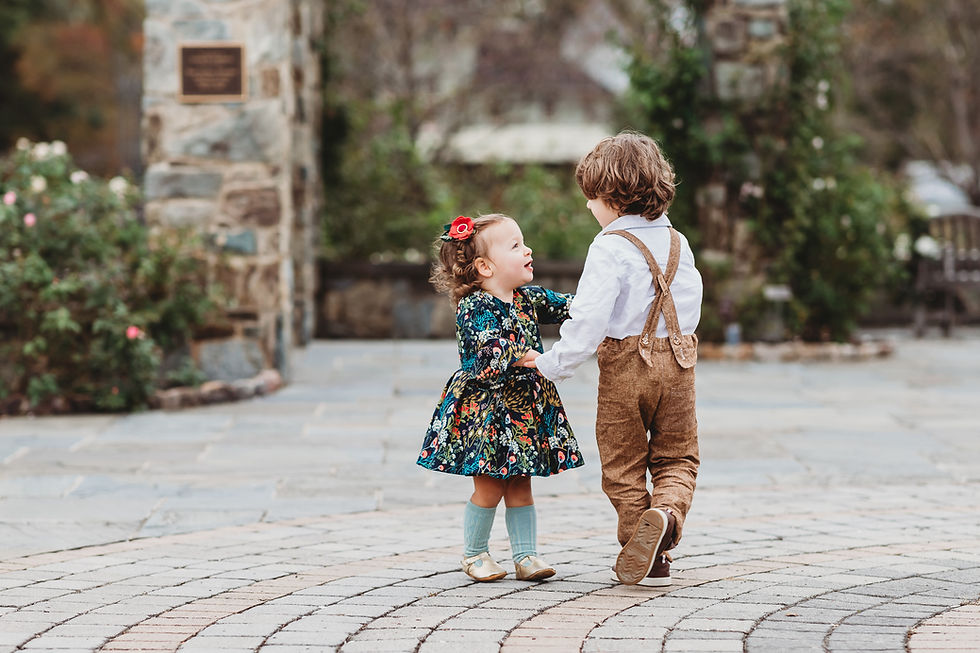 A little boy and girl dancing together outside on a cobble stone street.