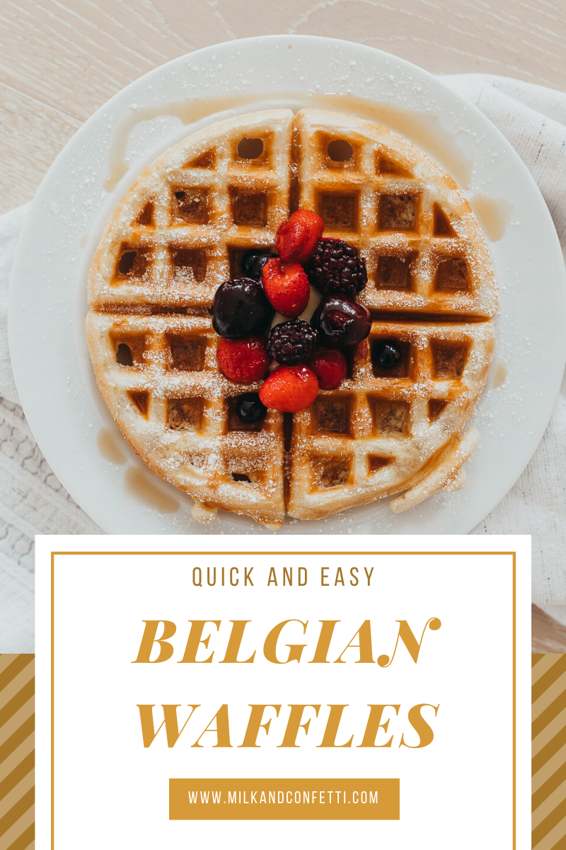 A homemade belgian waffle topped with berries and syrup on a white plate.