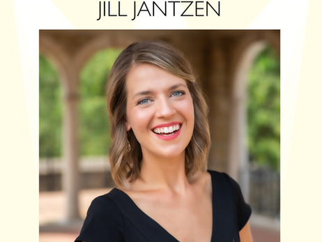 A smiling woman with short blonde hair wearing a black dress stands outdoors under stone archways. Green trees and soft architectural details appear blurred in the background. The text above her reads “Member Spotlight – Jill Jantzen.”