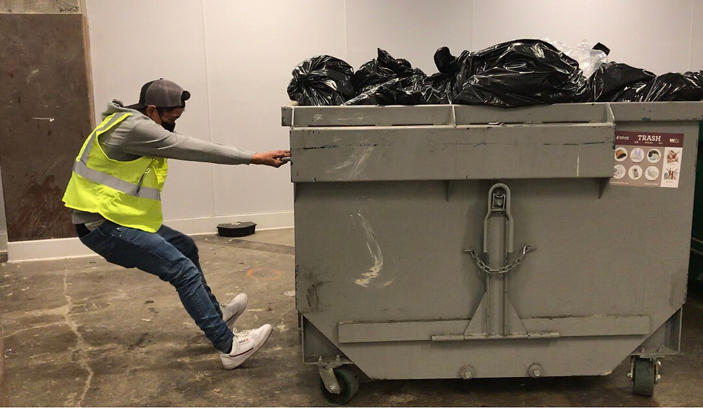 person pulling out a dumpster incorrectly