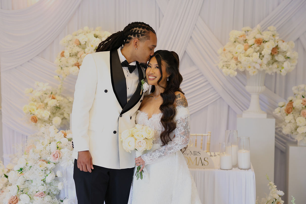 A couple at The Orangery wedding venue in maidstone with wedding decoration by Cloud Sixty Events they are surrounded by white drapery and white and pink florals in front of a sweetheart top table