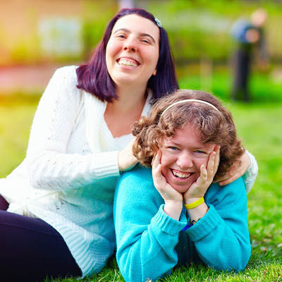 two female friends smiling and lying in the grass at the park
