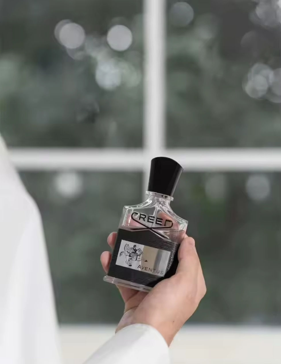 Holding a Creed fragrance bottle, the bottle with CREED text