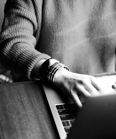 Mãos femininas em posição de digitação em um notebook com vista frontal.