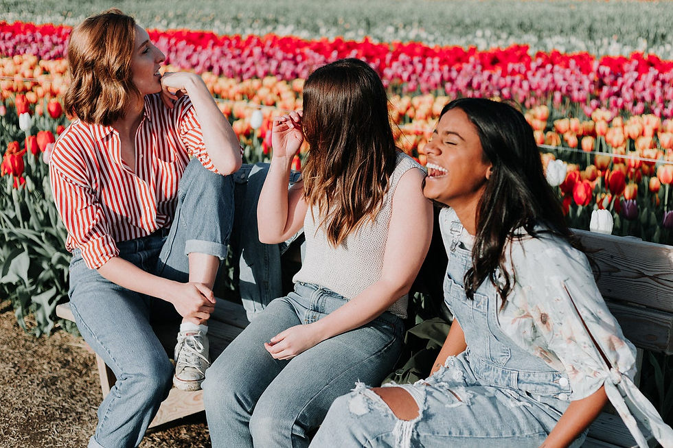 girl friends hanging out in a field of flowers laughing and supporting each other