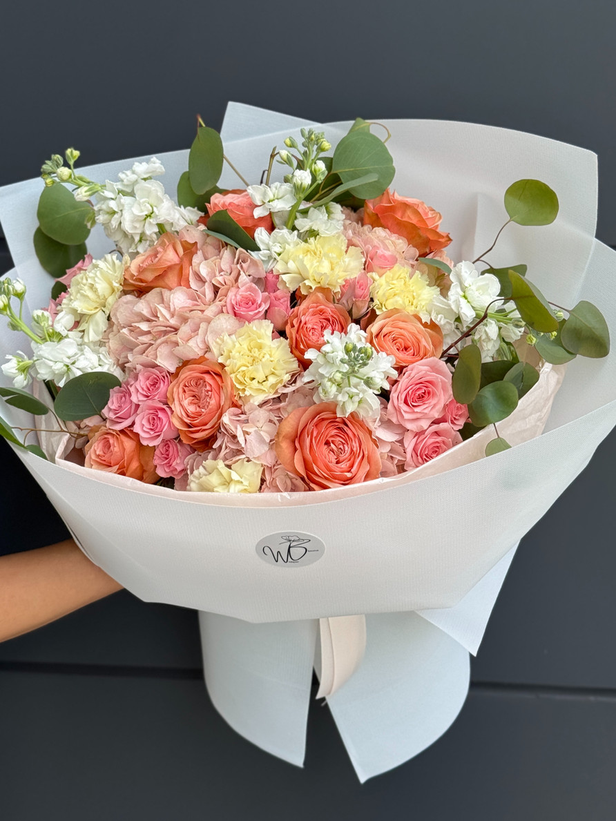 A lively bouquet of multi-toned roses, carnations, stock flowers, and eucalyptus.