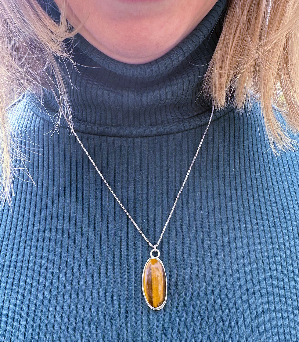 Thumbnail: Tiger eye pendant on sterling silver necklace worn by woman in green turtleneck