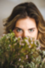 Vrouw met groene ogen houdt bloemen voor haar gezicht, symbool voor natuurlijke zelfzorg en innerlijke rust.