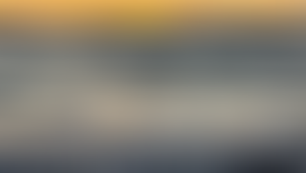 A close up shot of water reaching the shore with a light chop on the water and the last orange light of day setting in the distancet of day