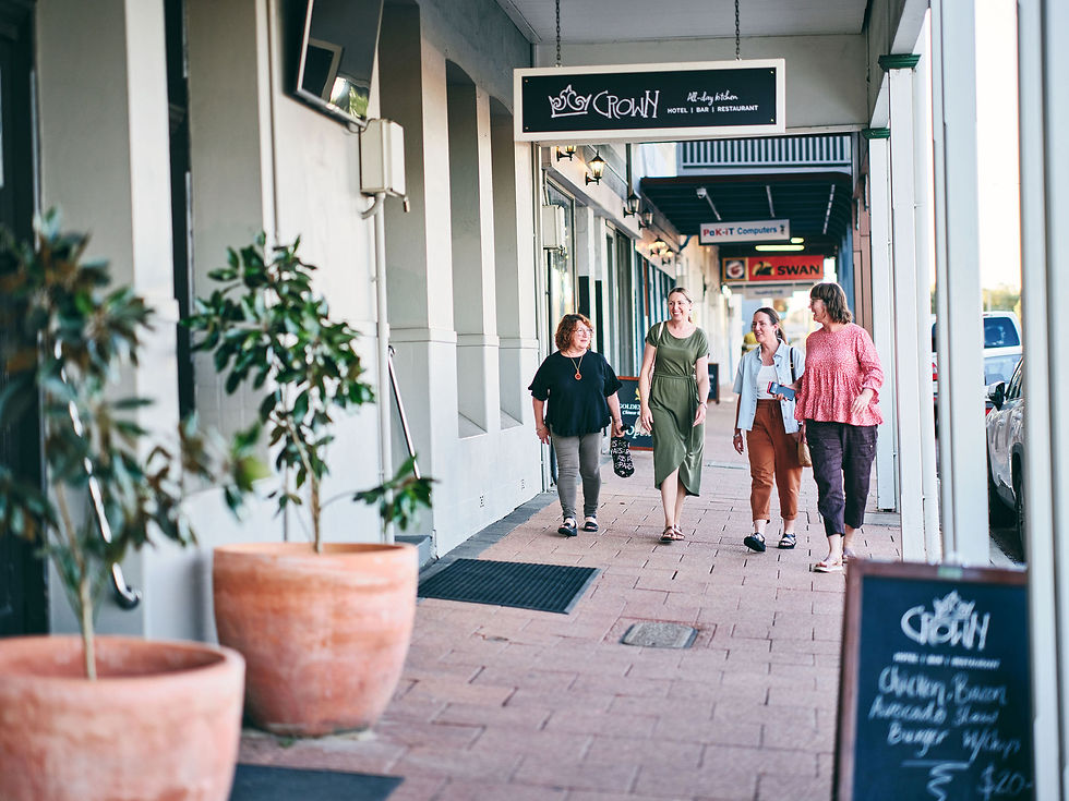 A cheerful tour group strolls along Throssell Street in Collie, where shopfronts glow with local pride in the town, long known for powering the state. Pic by Russell Ord