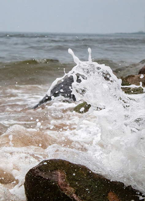 Macro image of the tide breaking against rocks on the beach