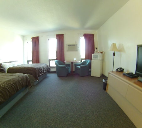 Hotel room with two beds, table, chairs, TV, and mini-fridge