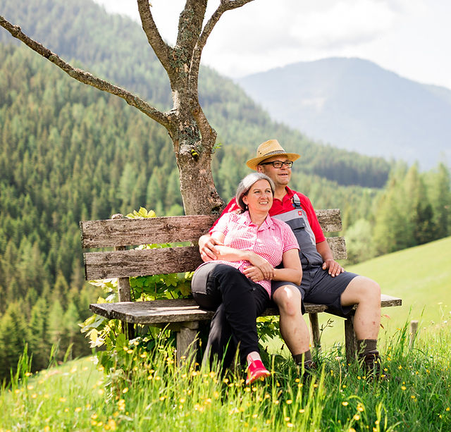 Älteres Paar sitzt auf Bank, Berglandschaft