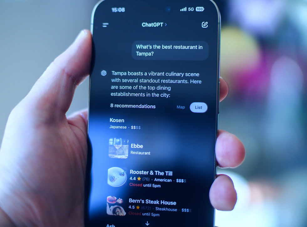 AI & SEO: Hand holds smartphone showing ChatGPT restaurant recommendations for Tampa, with a dark screen listing dining spots.