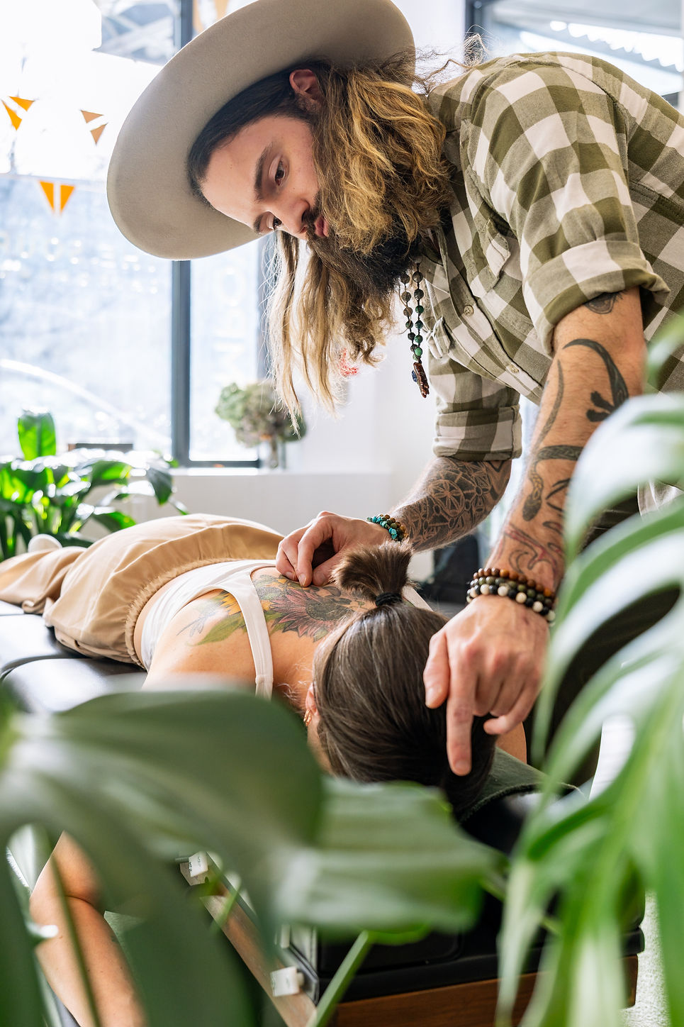 Doctor Chris is using gentle contact to ease tension in a woman's back and neck, guided by breath and nervous system regulation.