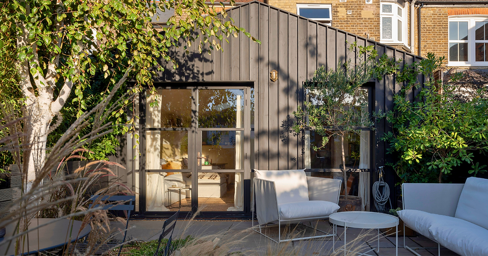 Rear extension clad with dark birch with crittal doors with garden furniture and greenery