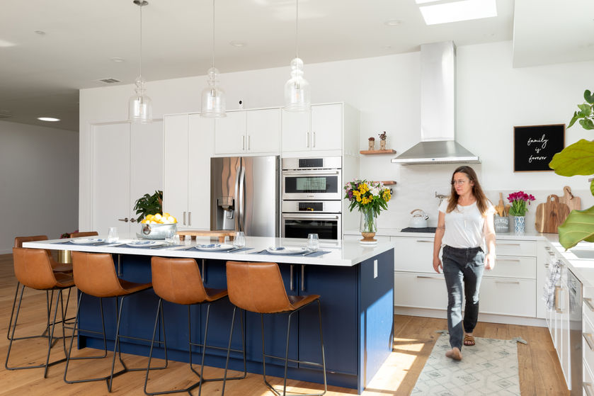 Modern kitchen with navy island, white cabinetry, and floating wood shelves.