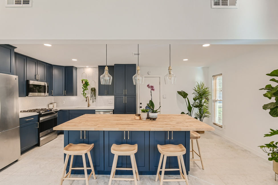 Updated kitchen with blue cabinetry, large wood island and pendant lighting