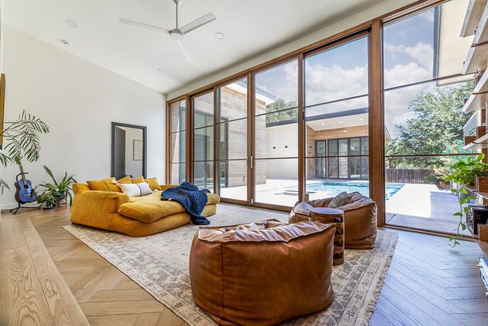 Modern sunroom addition with expansive windows, lounge seating and backyard views