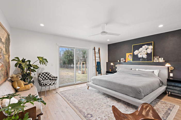 Primary bedroom with a dark accent wall, neutral furnishings, and contemporary décor.