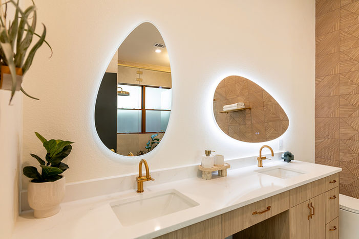 Custom double vanity with asymmetrical mirrors and brass fixtures