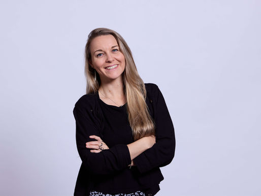 A professional woman in a long sleeve black top smiles at the camera