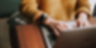 background image of hands typing on a laptop keyboard