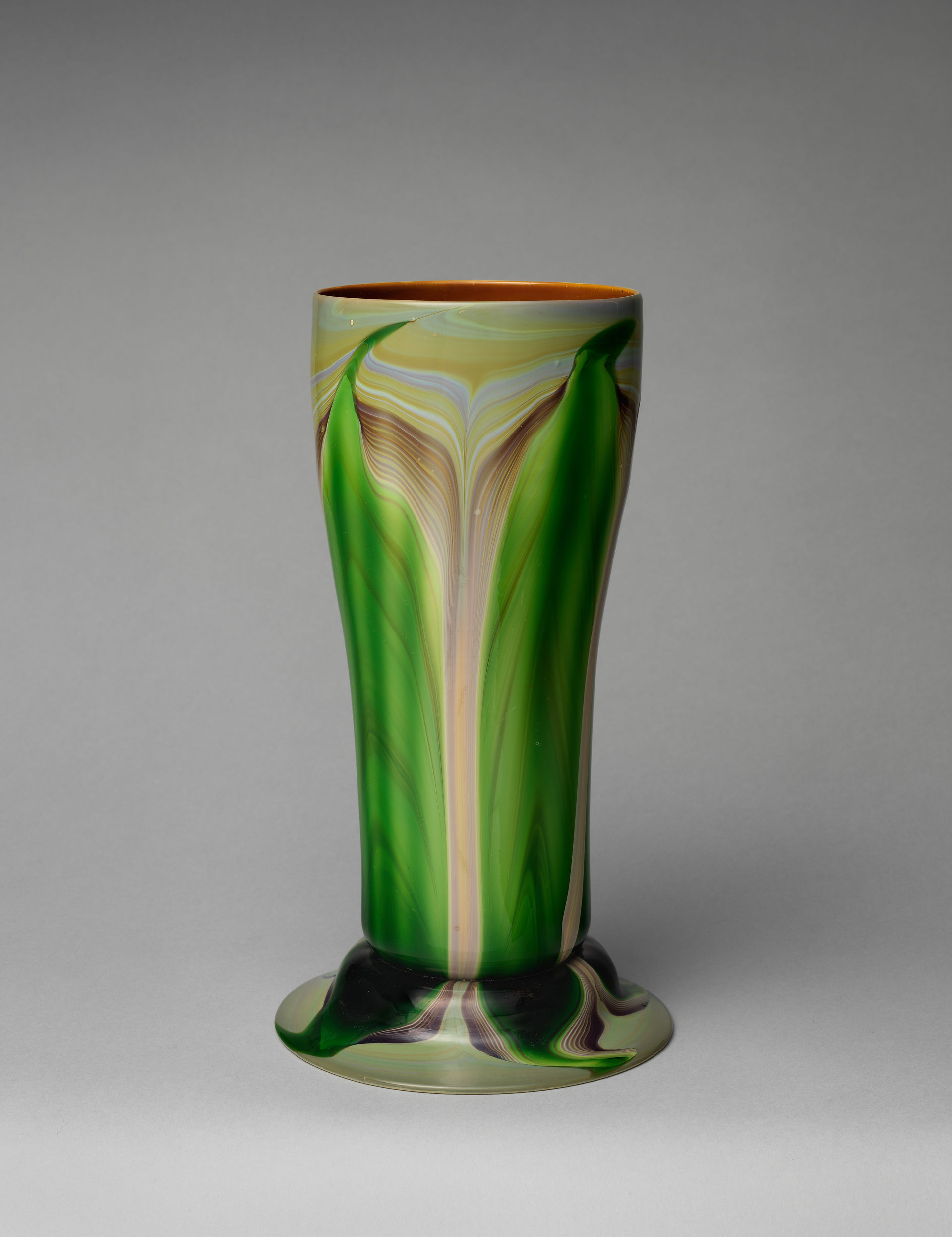 Alto vaso di vetro verde con linee fluide color crema, bordo leggermente svasato e ampio piede irregolare.