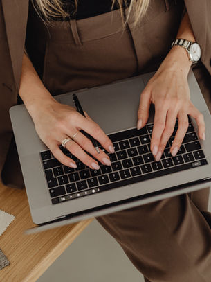 Hands typing on a laptop beside a table with material samples.