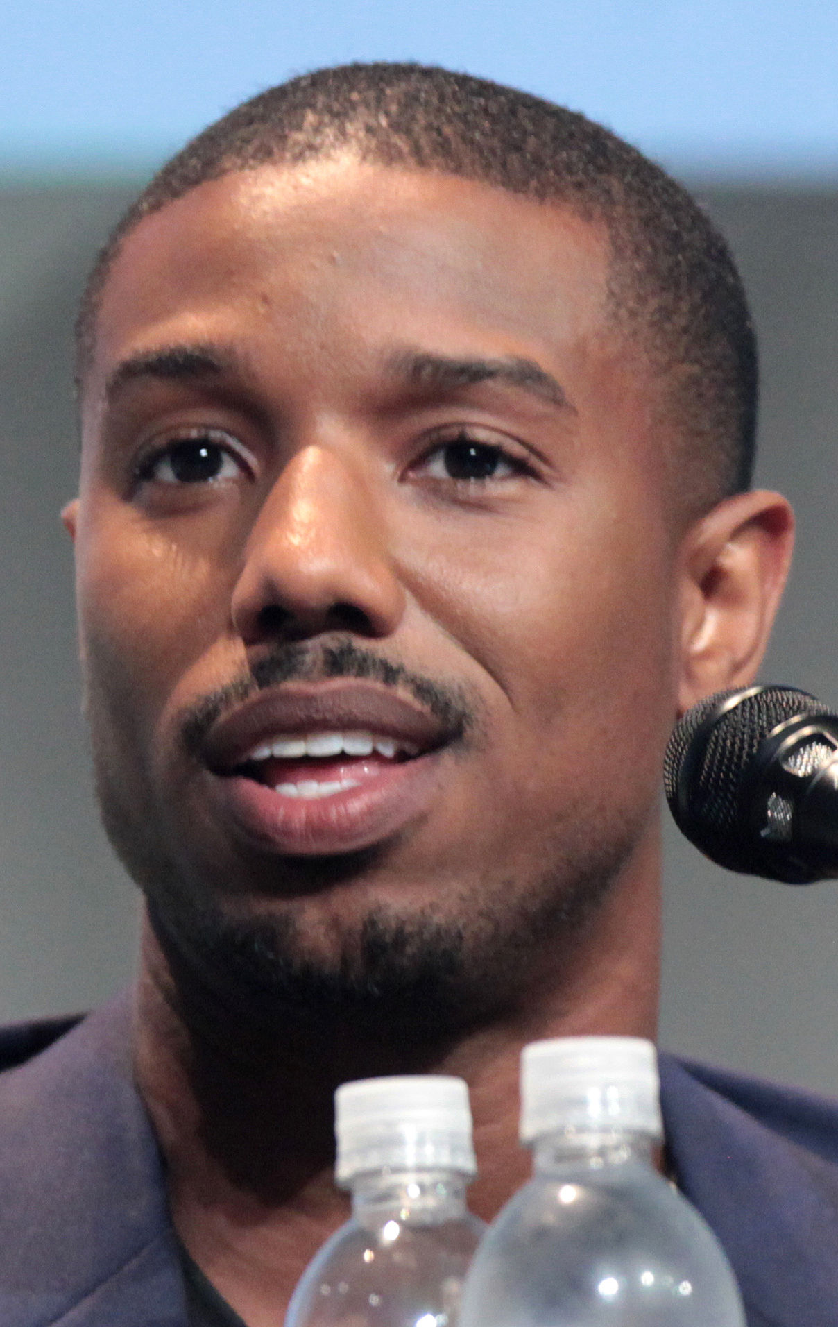 Michael B. Jordan speaking at a microphone at the 2015 San Diego Comic-Con. Archive photograph.