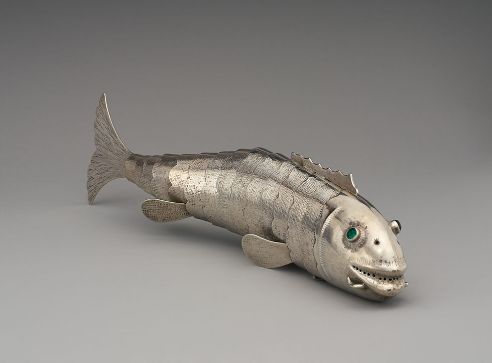 Angled view of the silver fish-shaped spice container showing its head, fins and tapering body.