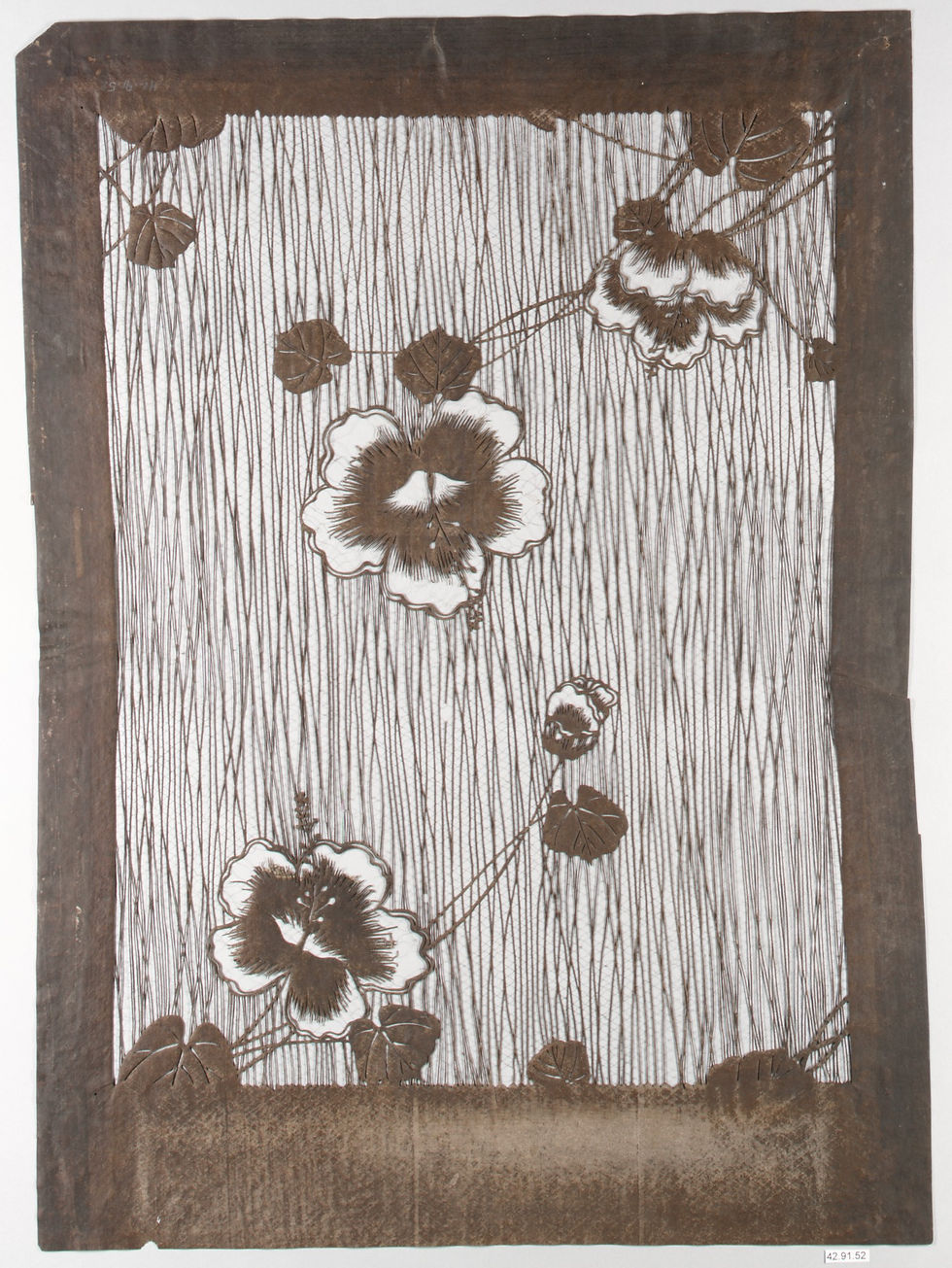 Tall paper stencil with flowers against a field of narrow vertical lines.